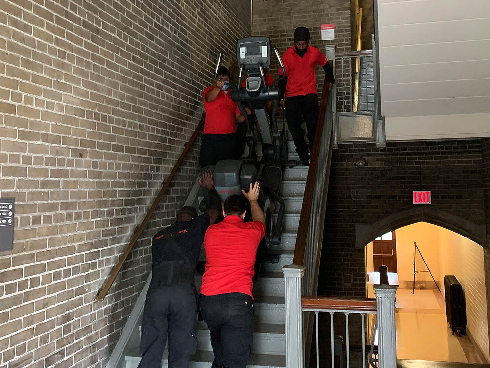 Staff moving commercial fitness equipment